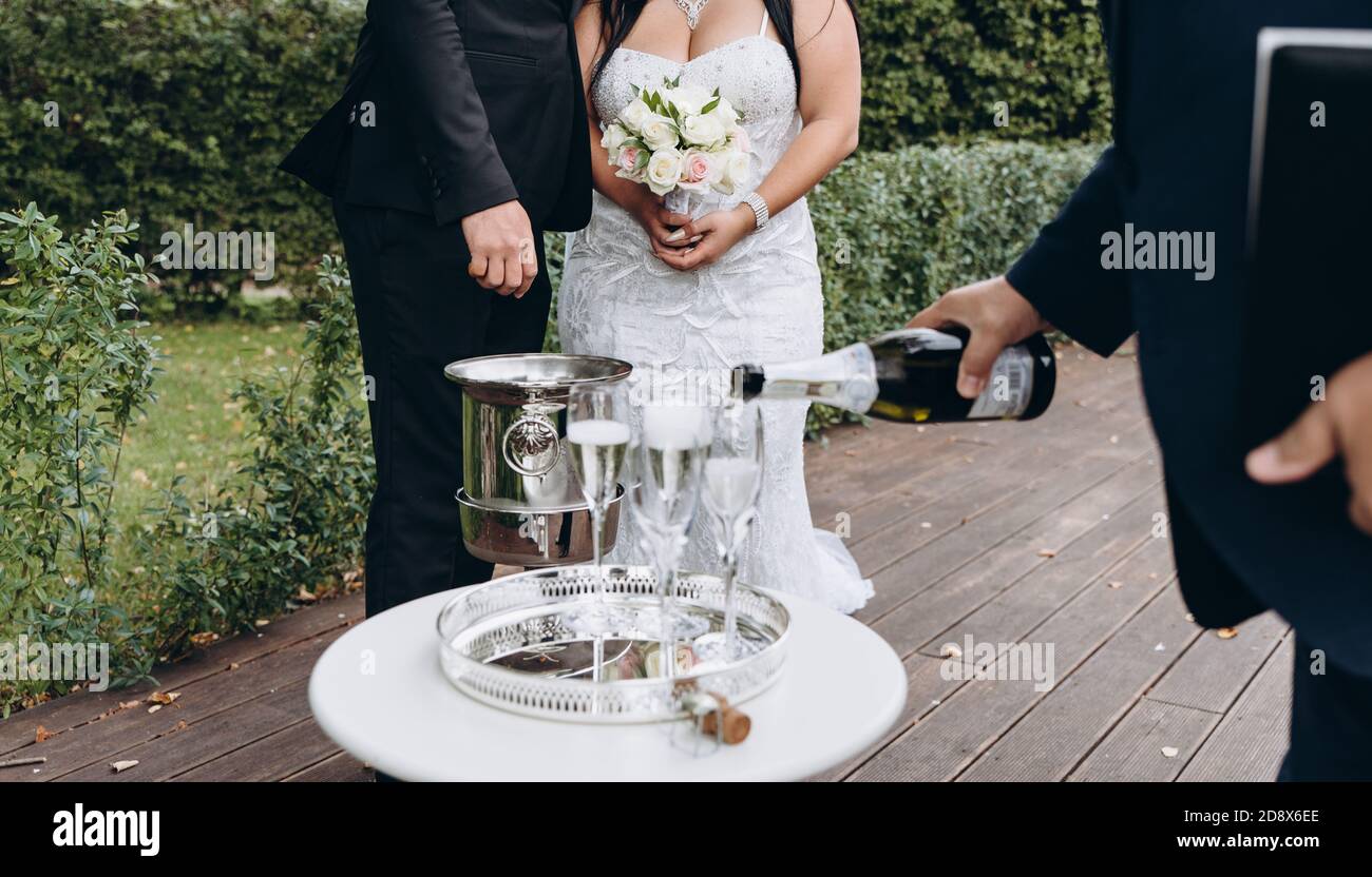 Il registrar del matrimonio riempirà i bicchieri con champagne per una felice coppia nuziale. Foto Stock