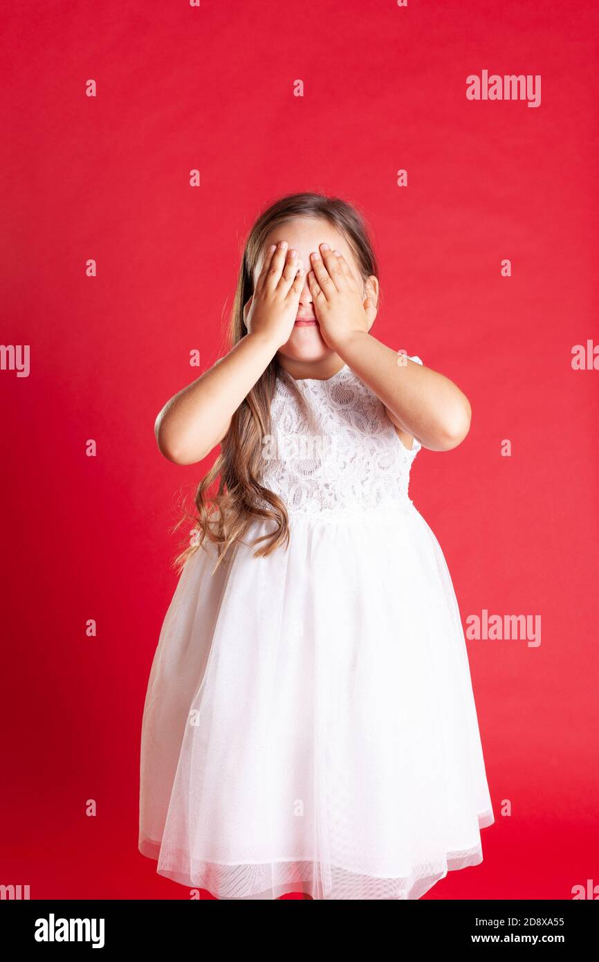 ragazza con capelli ondulati e vestito da sposa bianco la copre occhi con le mani in attesa di una sorpresa o un regalo Per Natale Foto Stock ragazza con capelli ondulati e vestito da sposa bianco la copre occhi con le mani in attesa di una sorpresa o un regalo Per Natale Foto Stock