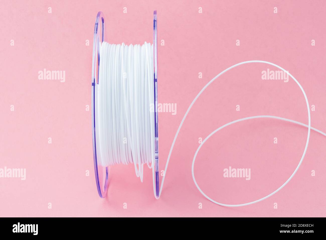 Filamento in plastica per stampante 3D. Bobina di filo termoplastico bianco per la stampa 3D da vicino isolata su sfondo rosa Foto Stock