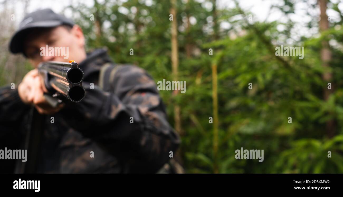 Hunter mira un fucile da caccia in una foresta Foto Stock
