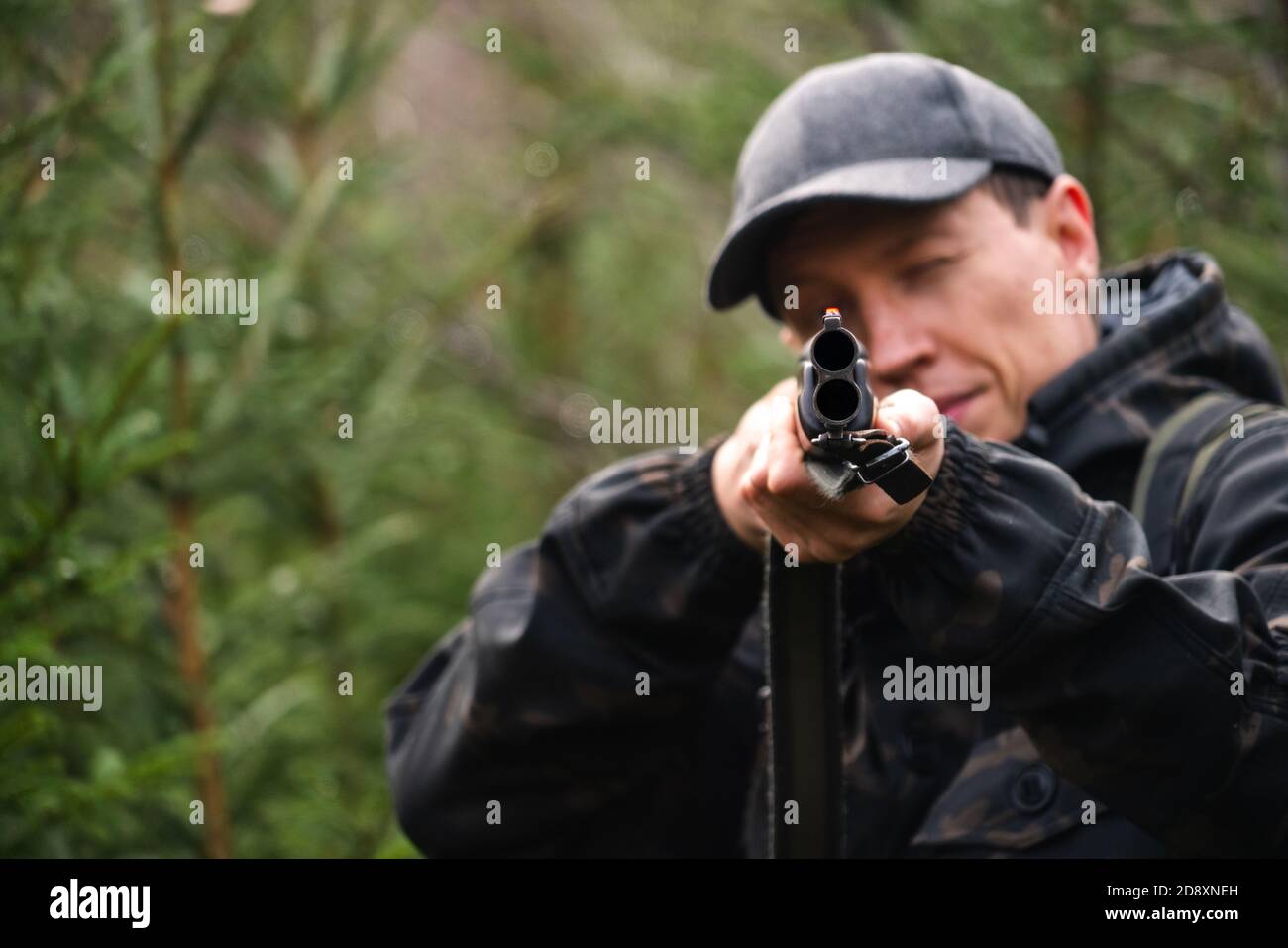Hunter mira un fucile da caccia in una foresta Foto Stock