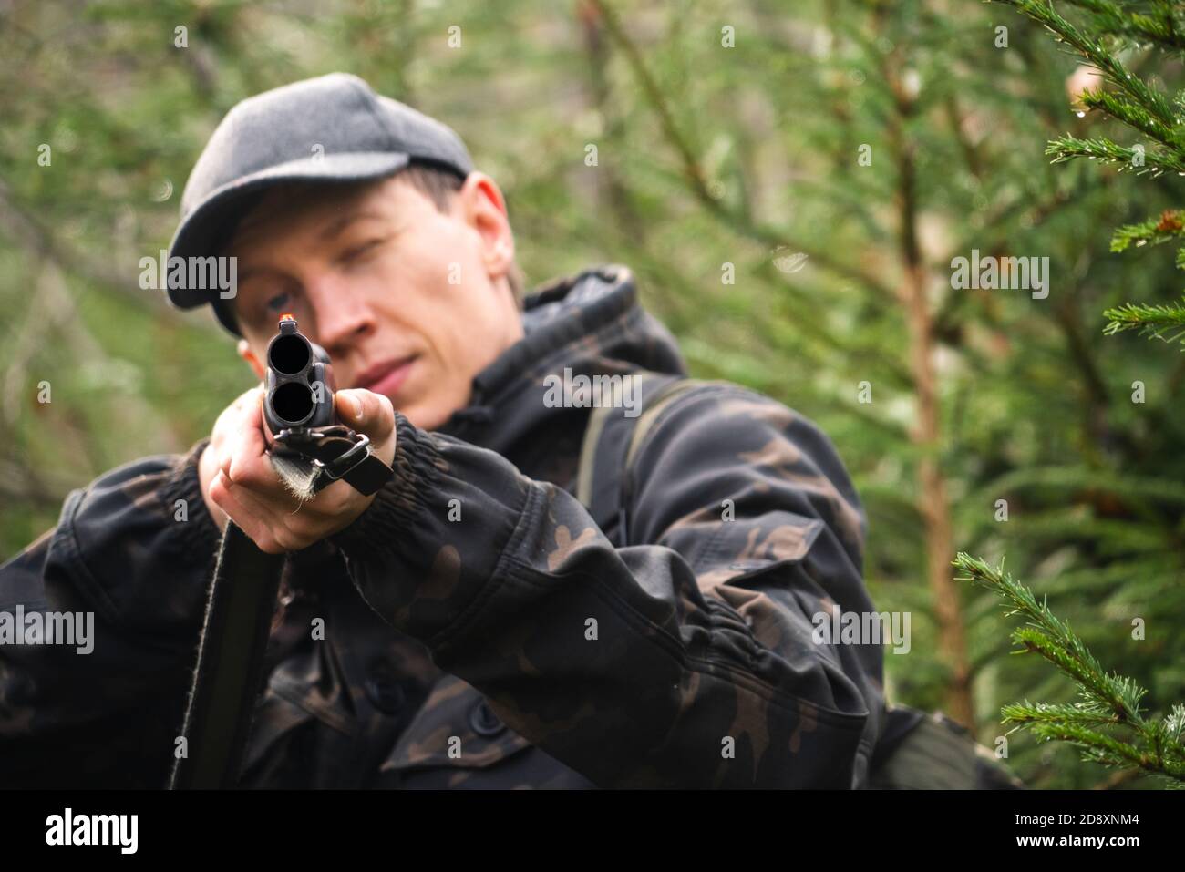 Hunter mira un fucile da caccia in una foresta Foto Stock