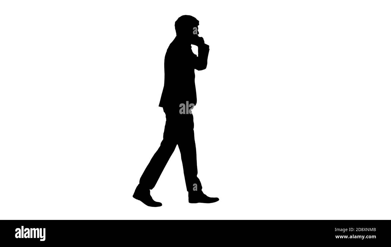 Scatto a tutta lunghezza. Vista laterale. Silhouette giovane uomo d'affari che parla al telefono mentre cammina. Riprese professionali con risoluzione 4K. 047. È possibile utilizzarlo Foto Stock