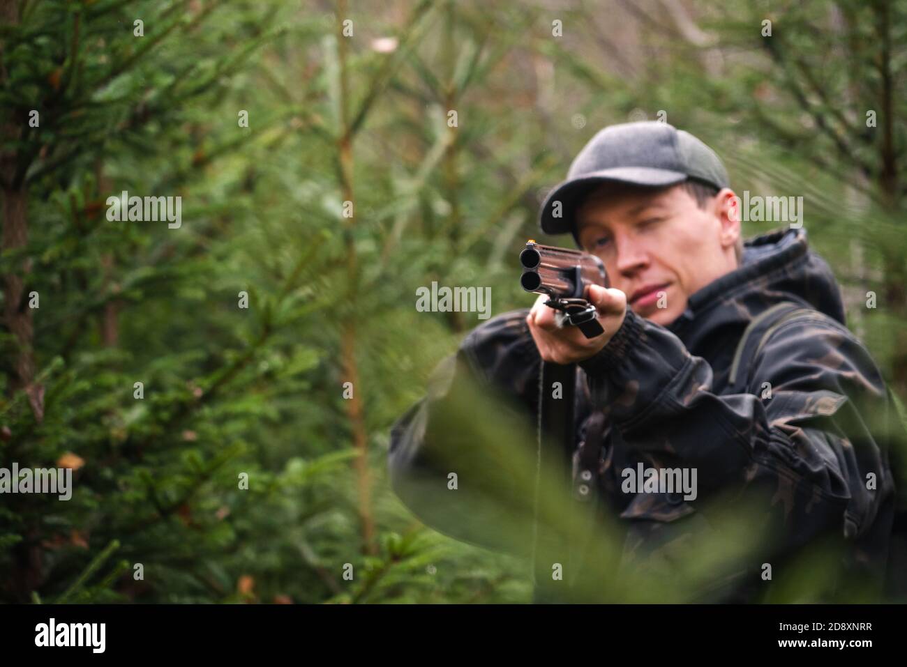 Hunter mira un fucile da caccia in una foresta Foto Stock