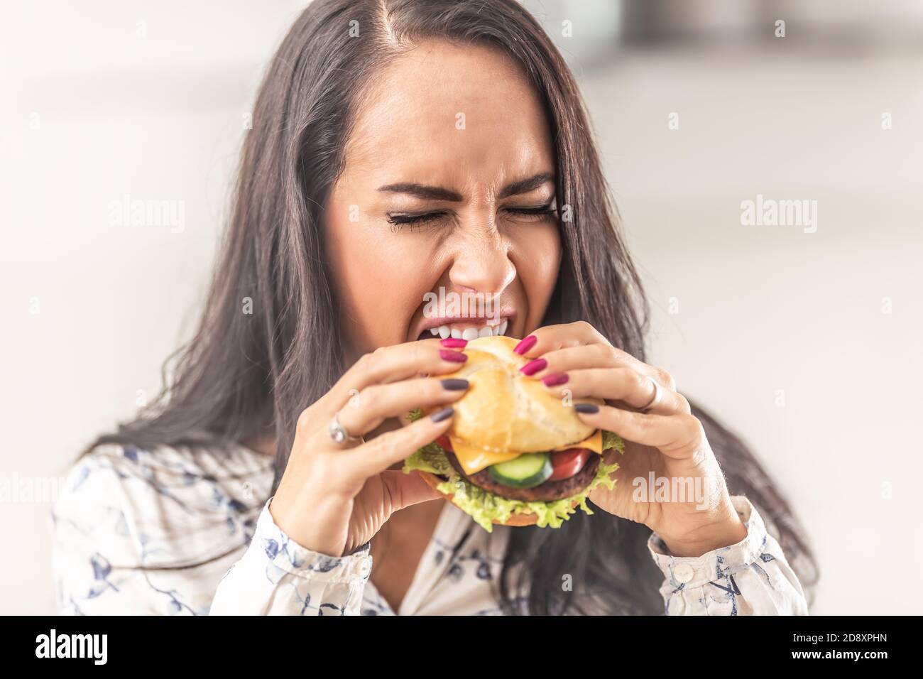 Ragazza cercando di aprire la sua bocca il più possibile per un hamburger grande. Foto Stock