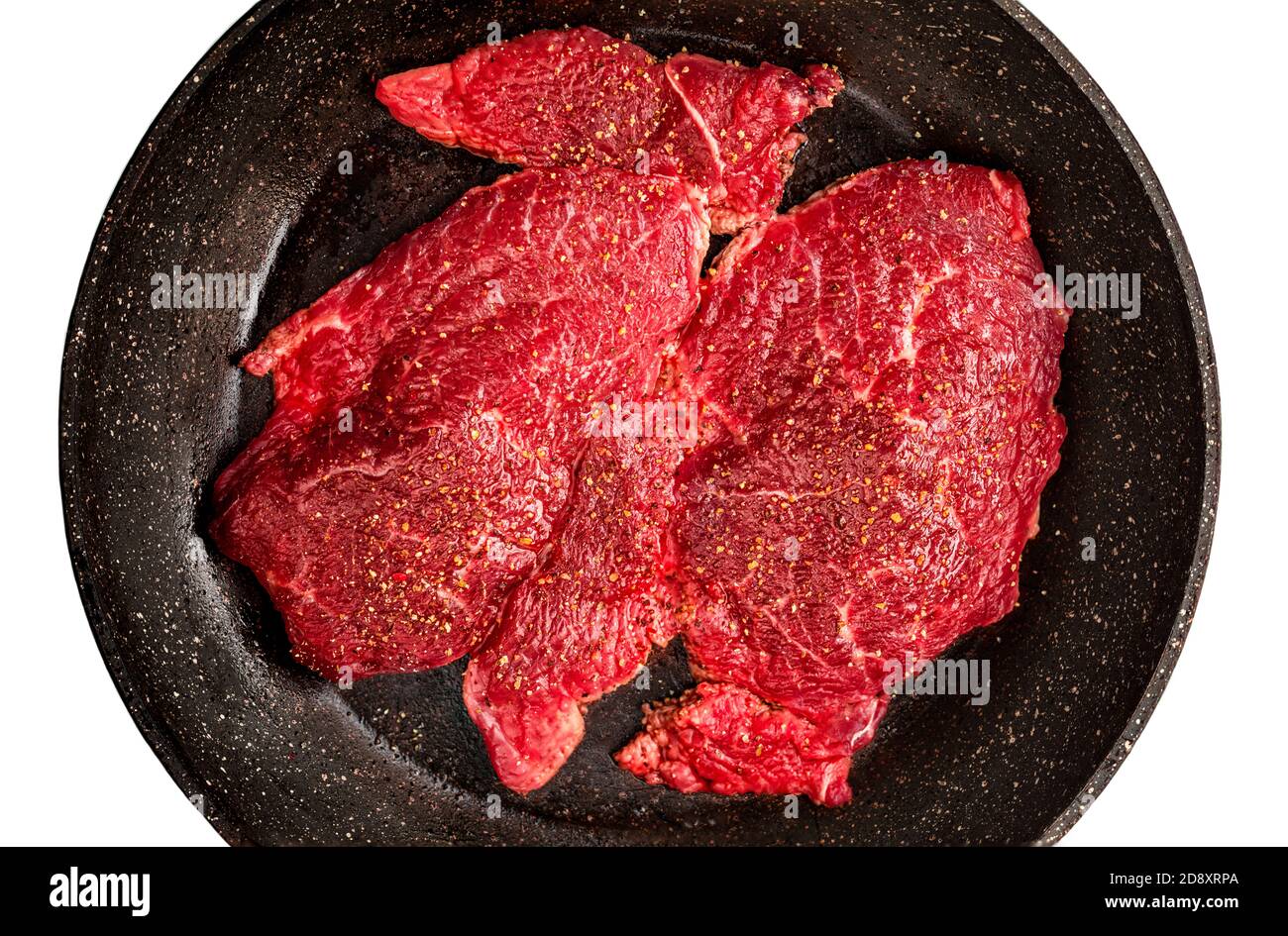 Bistecca di manzo fresco crudo su padella nera isolata su sfondo bianco, primo piano. Migliore vista dall'alto della carne di manzo Foto Stock