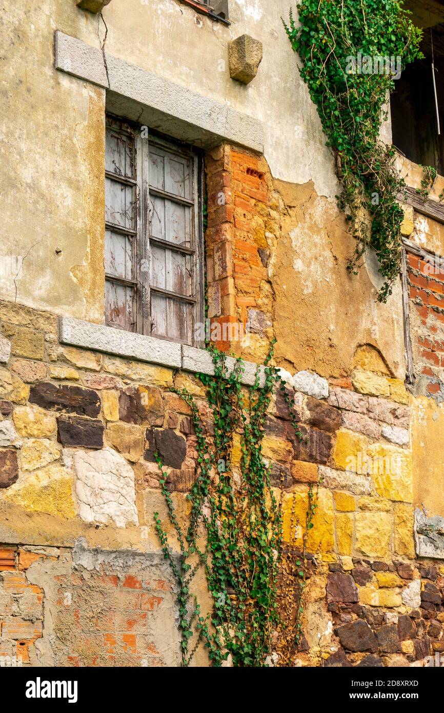 rovina incrinata con una parete danneggiata e una finestra con persiane chiuse in legno. Casa fatiscente per demolizione Foto Stock