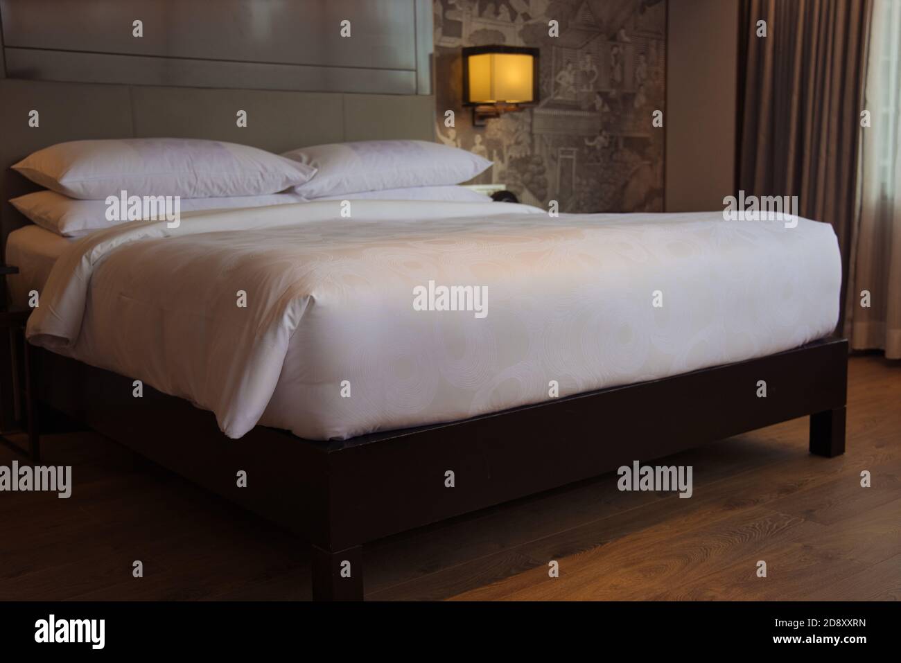 Questa foto unica mostra un grande letto in piedi in una camera d'hotel. Con comodini e belle lampade Foto Stock