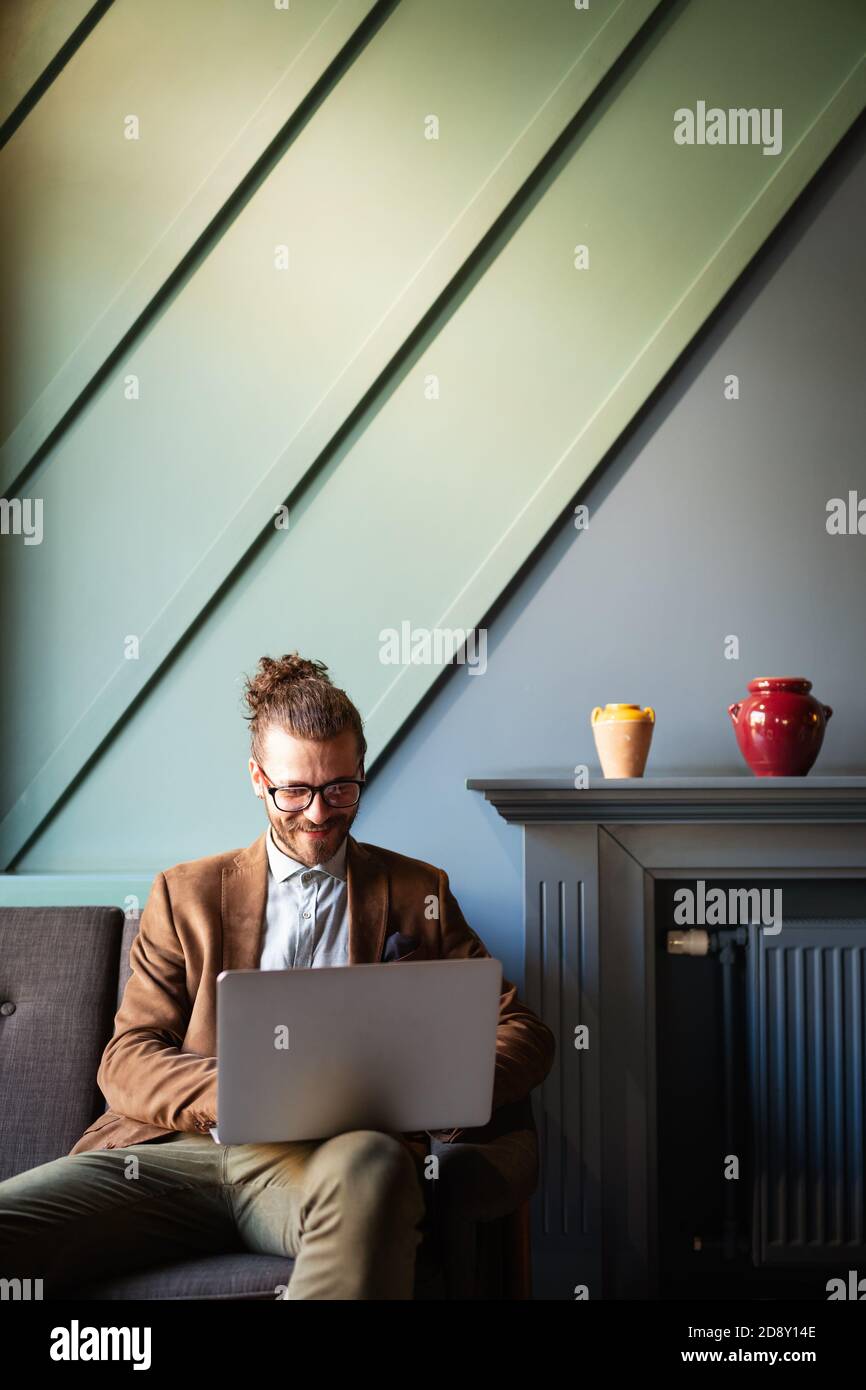 Ritratto di imprenditore bello sorridere mentre utilizzando computer portatile in ufficio Foto Stock