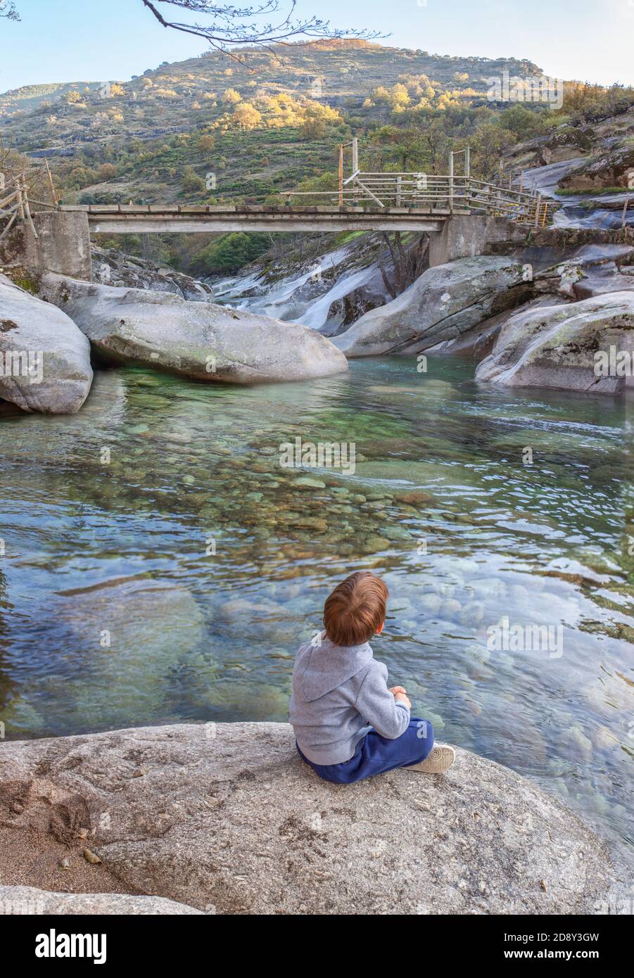 Piccolo ragazzo seduto sul lungofiume della gola di Los Pilones alla Riserva Naturale Garganta de los Infiernos. Posto eccezionale per godersi la natura Extremadura Foto Stock