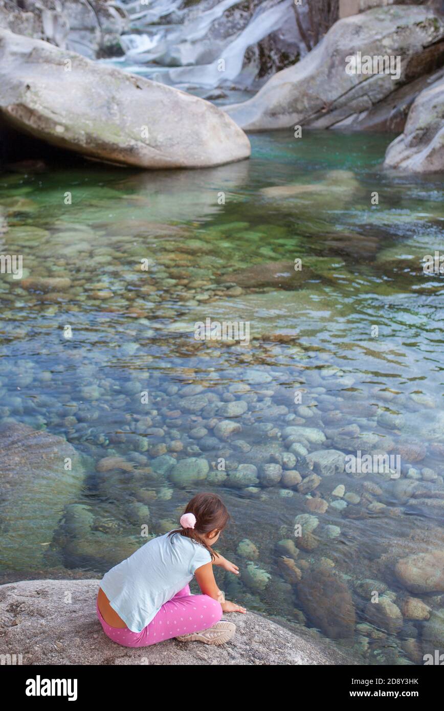 Bambina seduta sul lungofiume della gola di Los Pilones alla Riserva Naturale Garganta de los Infiernos. Posto eccezionale per godersi la natura Extremadura Foto Stock