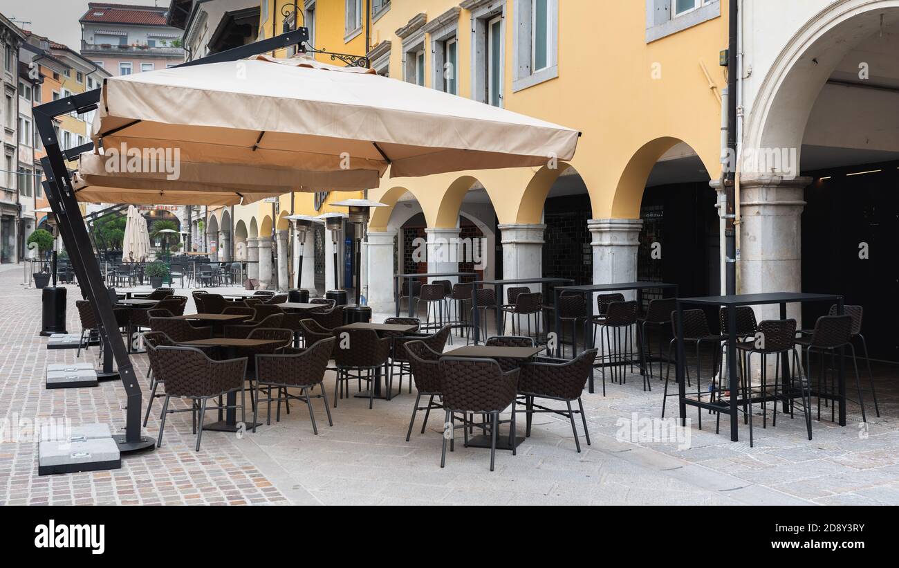 Via vuota in una città italiana durante il tempo di Covid-19. Atmosfera triste con nessuno seduto ai tavoli di un caffè all'aperto e bar. Blocco. Foto Stock