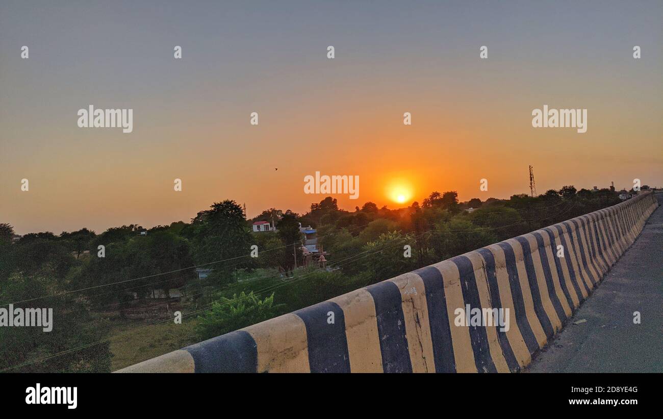 bel sole che sale cielo con strade asfaltate in ambiente rurale utilizzare il trasporto terrestre e di viaggio sfondo. Foto Stock