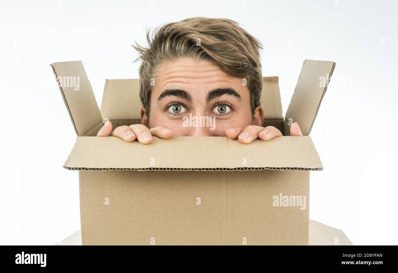 Ragazzo con un volto di sorpresa con la testa all'interno di una scatola di cartone. Foto Stock