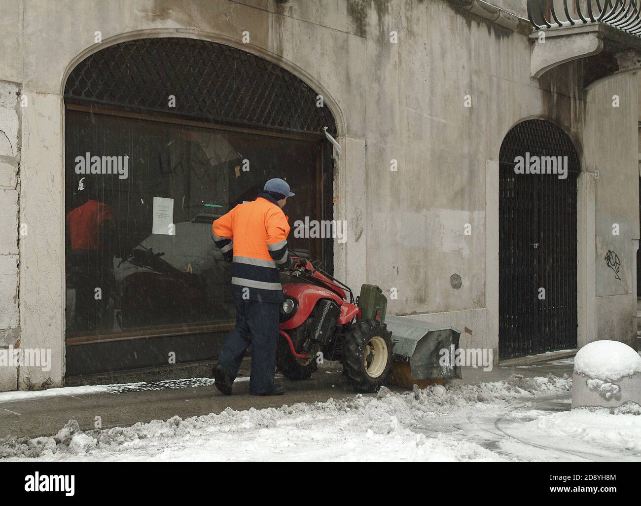 un dipendente comunale libera la neve dal marciapiede Foto Stock