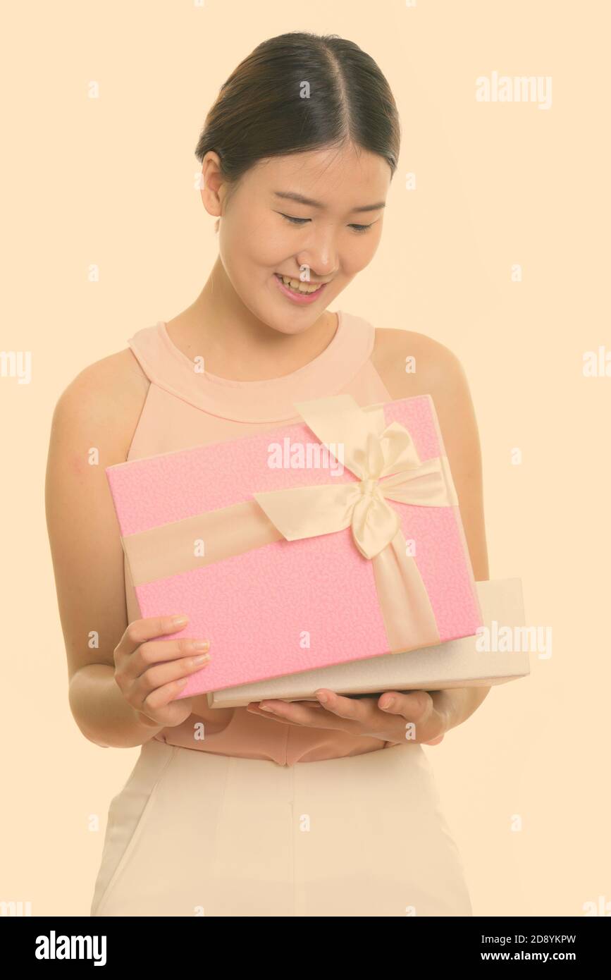 Studio scatto di giovane felice donna asiatica sorridente mentre apre scatola regalo Foto Stock