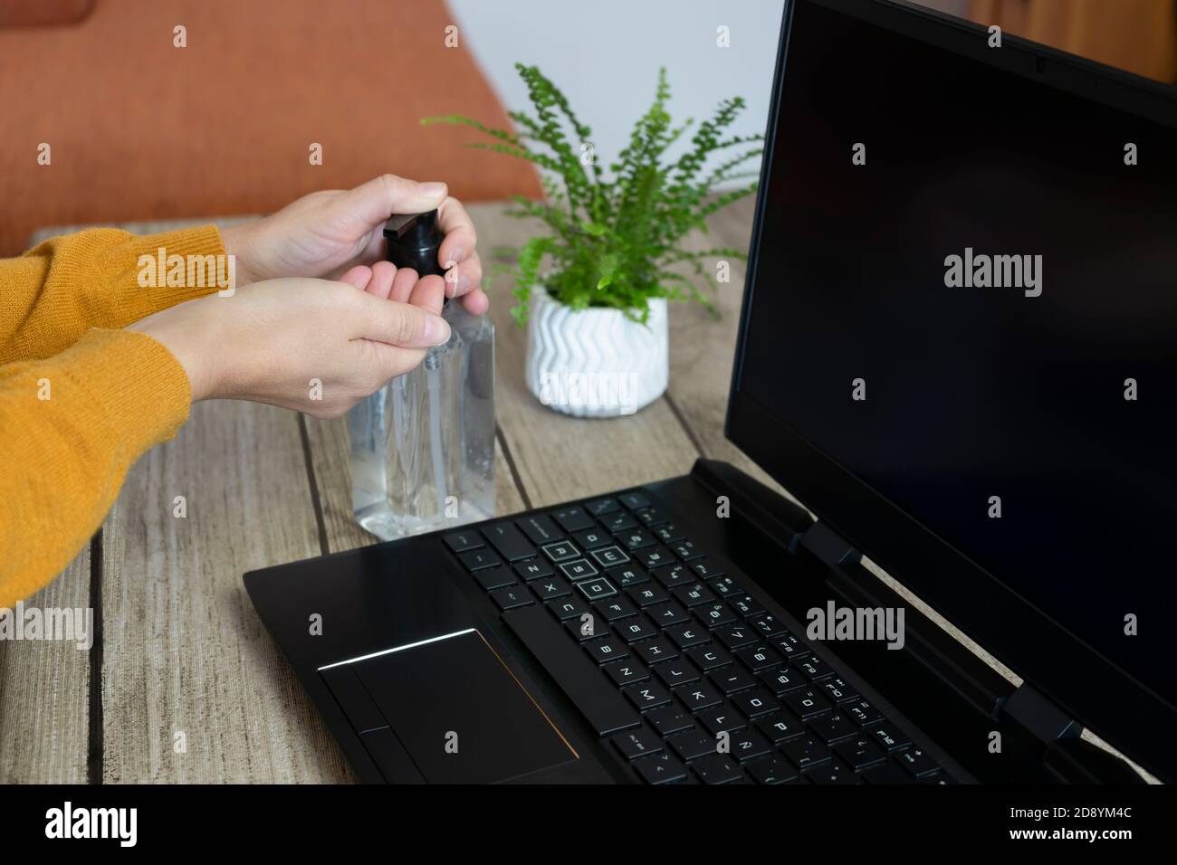 Donna che applica disinfettante per le mani o idrogel disinfettante le mani contro germi, coronavirus o covid-19, lavorando con il computer portatile a casa o in ufficio.Pandemic li Foto Stock