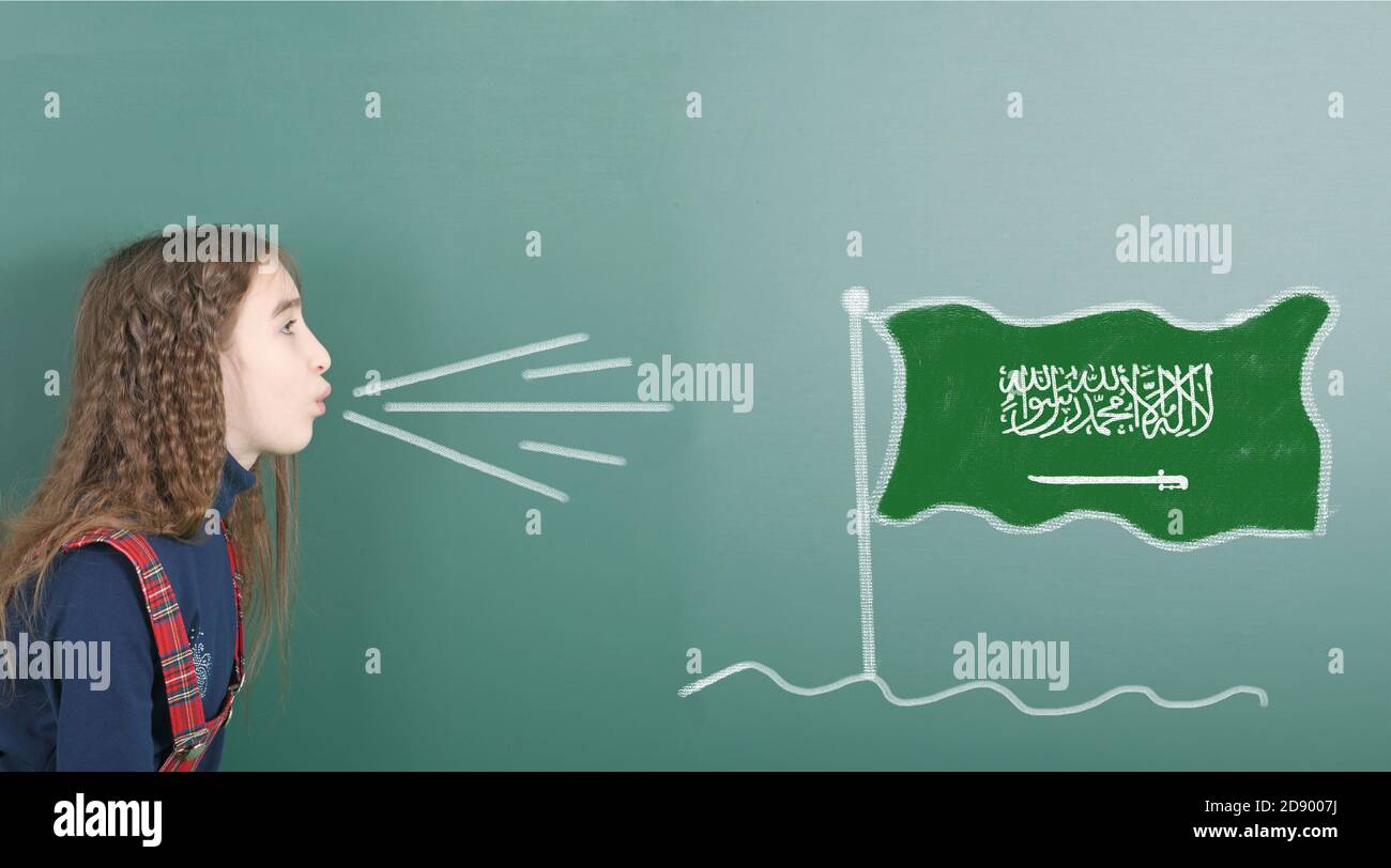 Ragazza pre-adolescente che soffia sul bordo della scuola disegnata sulla bandiera dell'Arabia Saudita lavagna. Foto ad alta risoluzione. Profondità di campo completa. Foto Stock