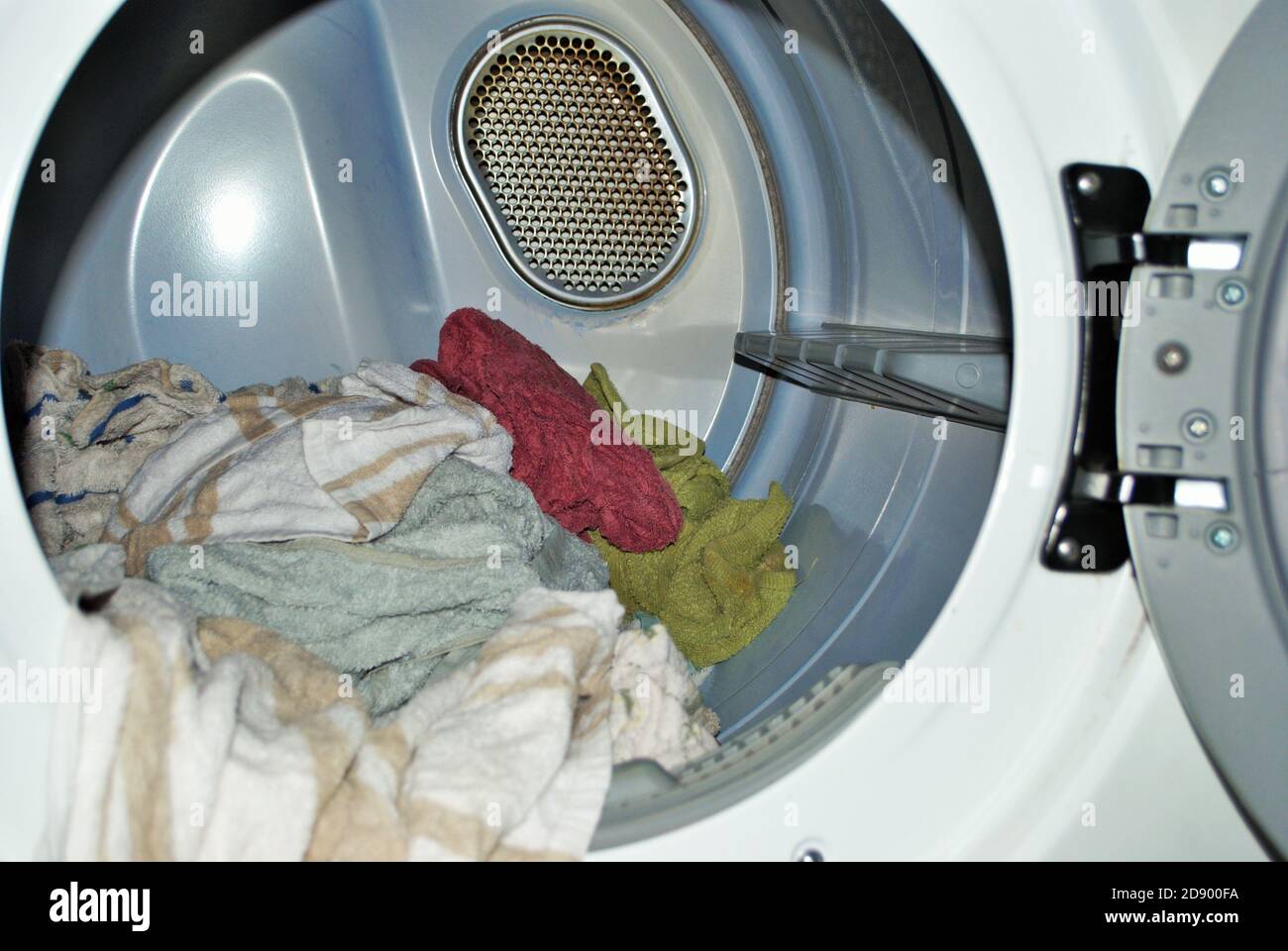 Carico di asciugamani bagnati che entrano nell'asciugatrice sulla lavanderia giorno Foto Stock