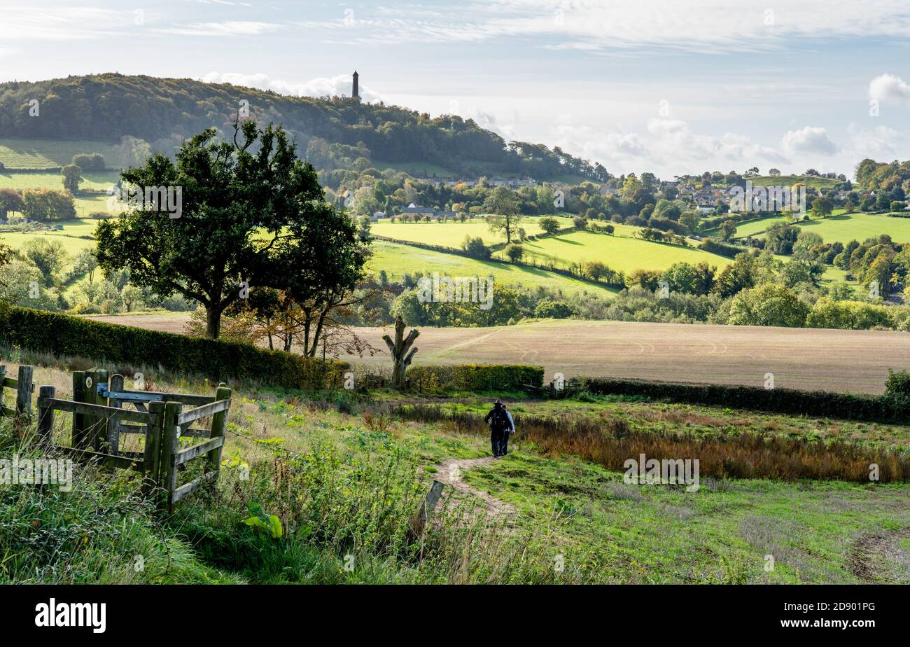 Camminatori sulla Cotswold Way vicino a North Nibley nel Gloucestershire Cotswolds in direzione del monumento di Tyndale in lontananza Foto Stock