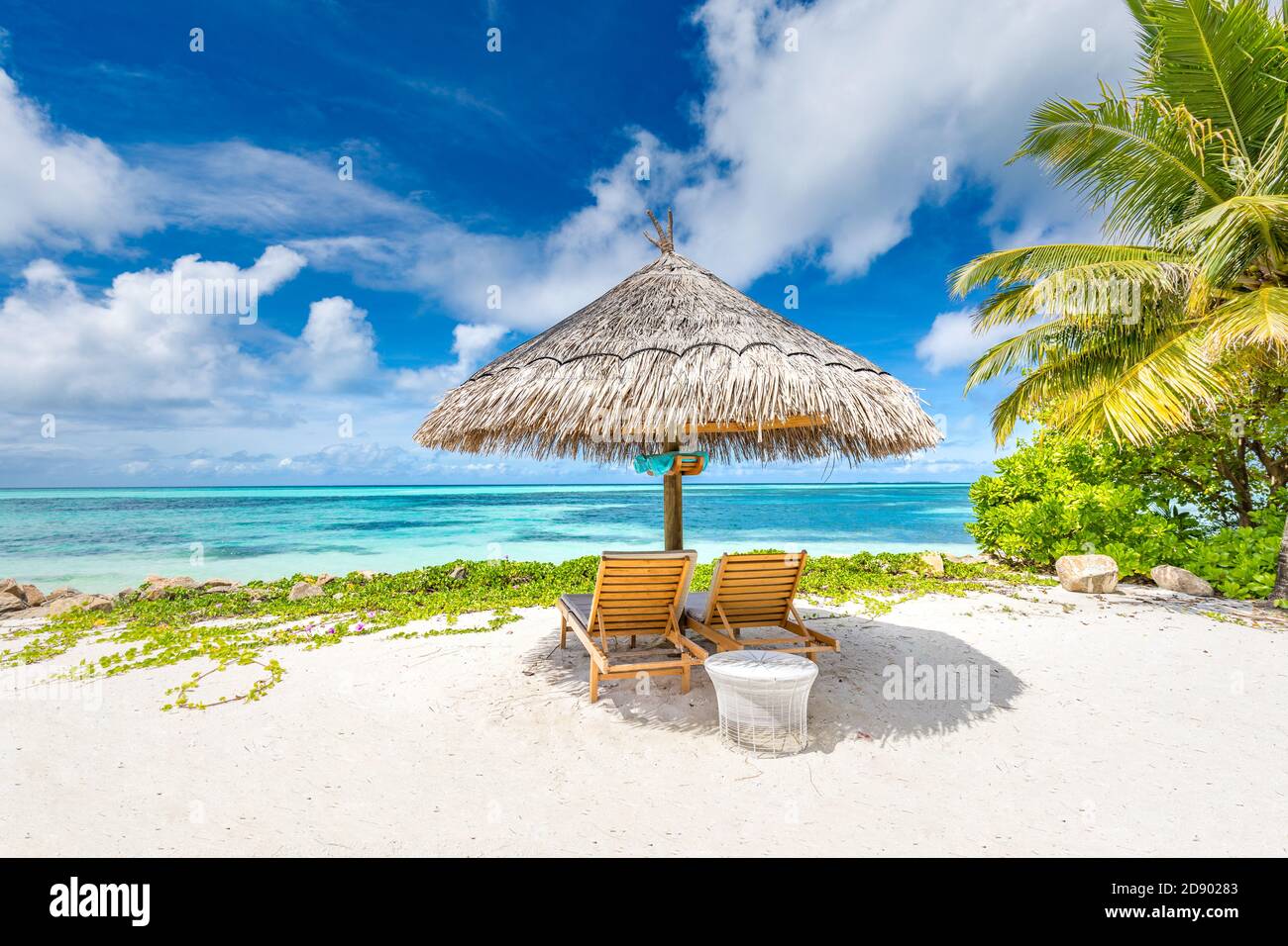 Sedie e ombrellone su una spiaggia con ombra da palme. Letti e ombrellone su una spiaggia tropicale, vacanza estiva di lusso, vacanza in coppia, vista idilliaca Foto Stock