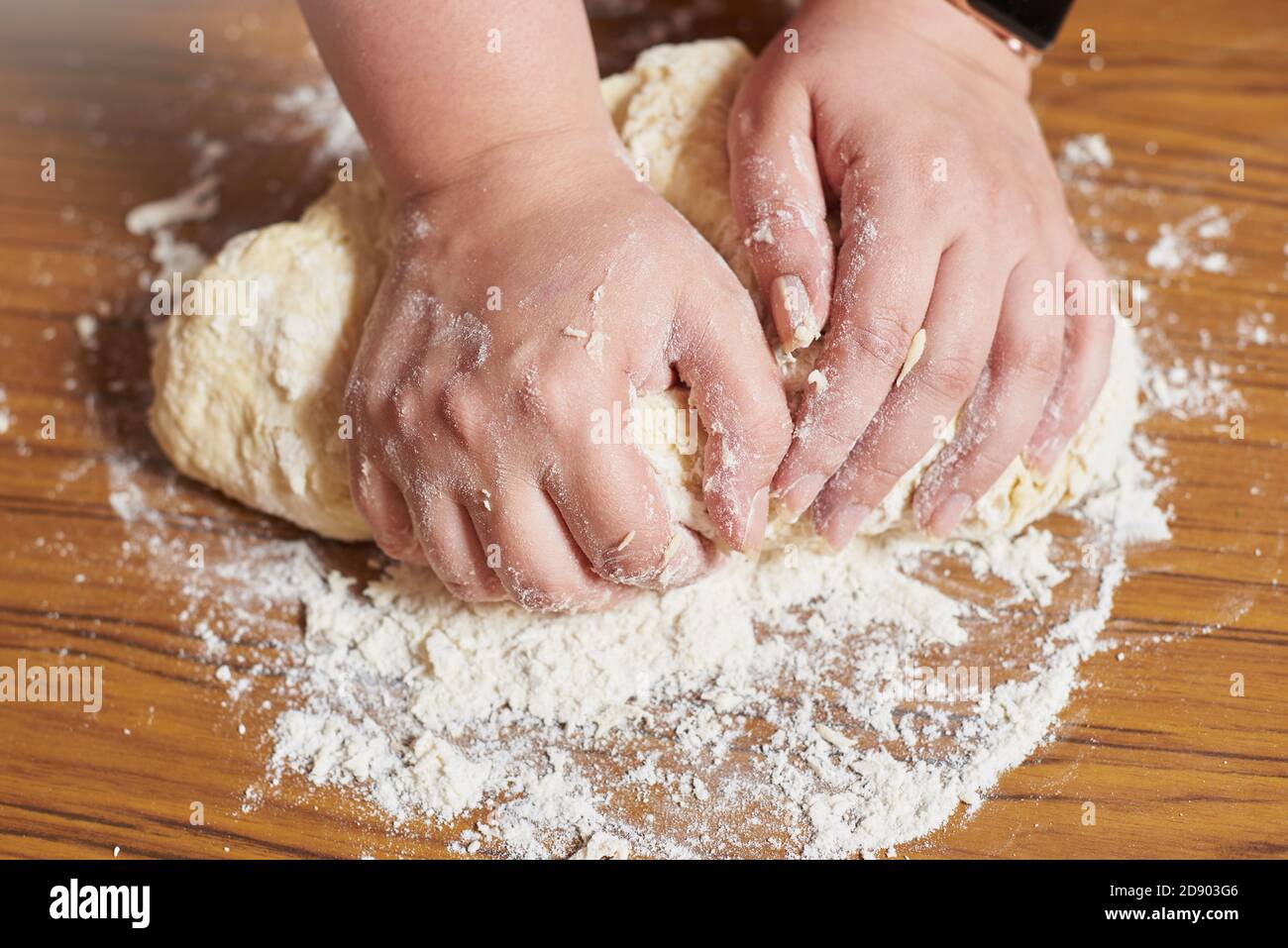 Primo piano dell'impasto per impastare le mani femminili a casa Foto Stock