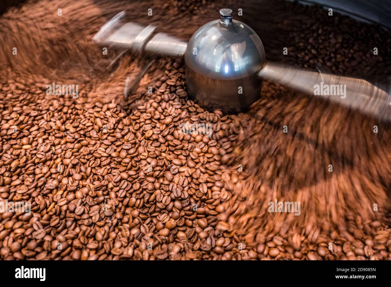 Tostatura dei chicchi di caffè. Chicchi di caffè aromatici appena tostati in una moderna macchina per tostare il caffè con una sfocatura Foto Stock