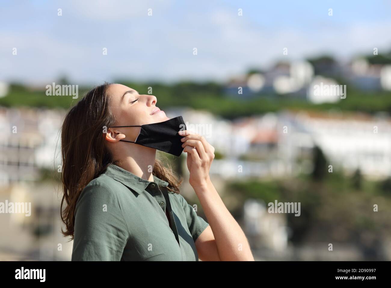 Donna rilassata togliendo la maschera respirando aria fresca in un città in vacanza Foto Stock
