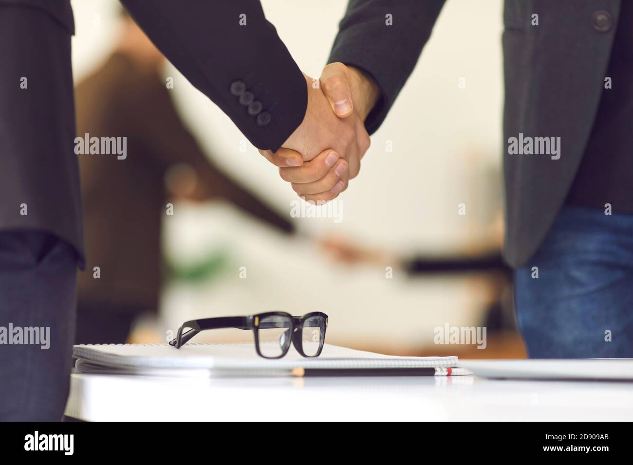 Primo piano di due uomini d'affari che scuotono le mani su un tavolo di negoziazione in ufficio. Foto Stock