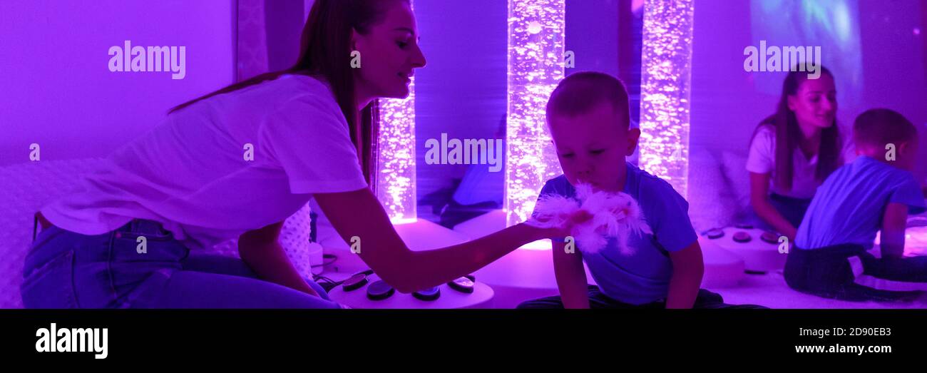 Bambino con disabilità intellettuale e il suo terapeuta in sala sensoriale stimolante, snoezelen. Bambino autistico che interagisce con il terapeuta durante la terapia Foto Stock