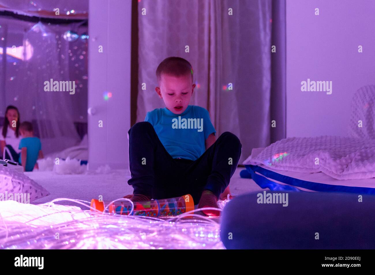 Bambino con disabilità intellettuale in sala sensoriale stimolante, snoezelen. Bambino autistico che interagisce durante la sessione di terapia. Foto Stock