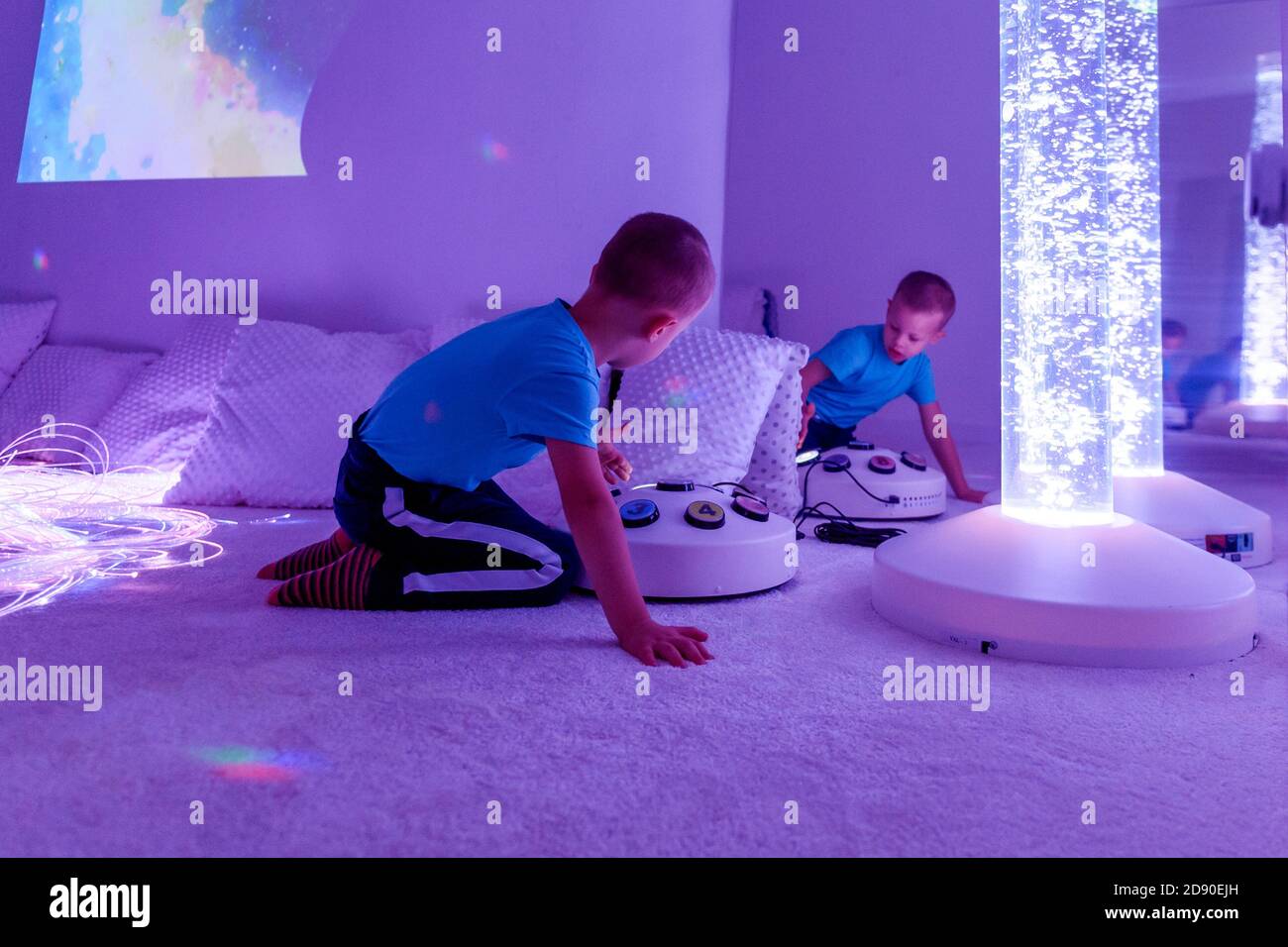 Bambino con disabilità intellettuale in sala sensoriale stimolante, snoezelen. Bambino autistico che interagisce durante la sessione di terapia. Foto Stock