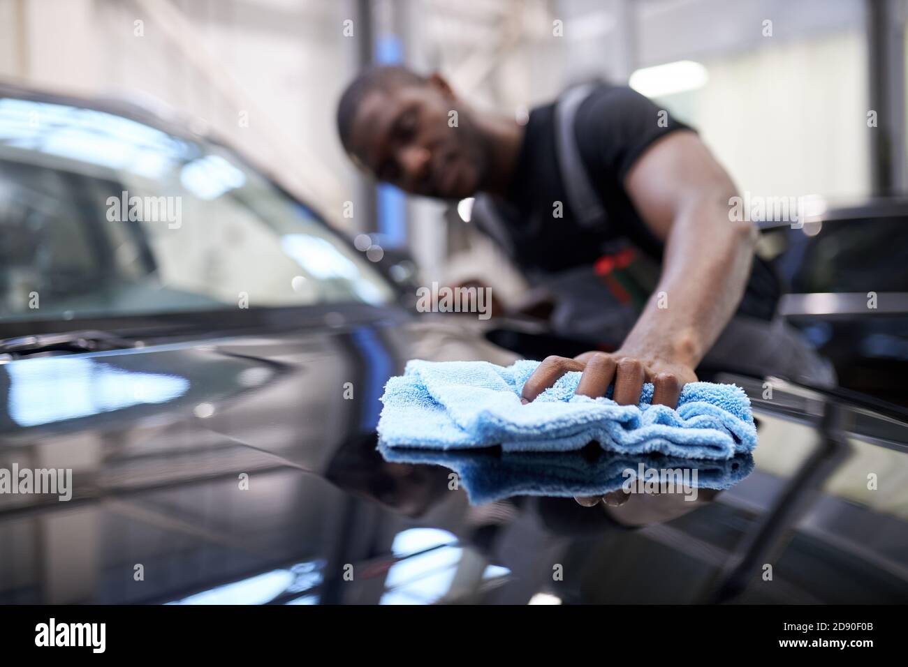 dettagli auto - l'uomo africano tiene una lucidatrice in mano e lucida l'auto, mettere a fuoco su stoffa. primo piano Foto Stock
