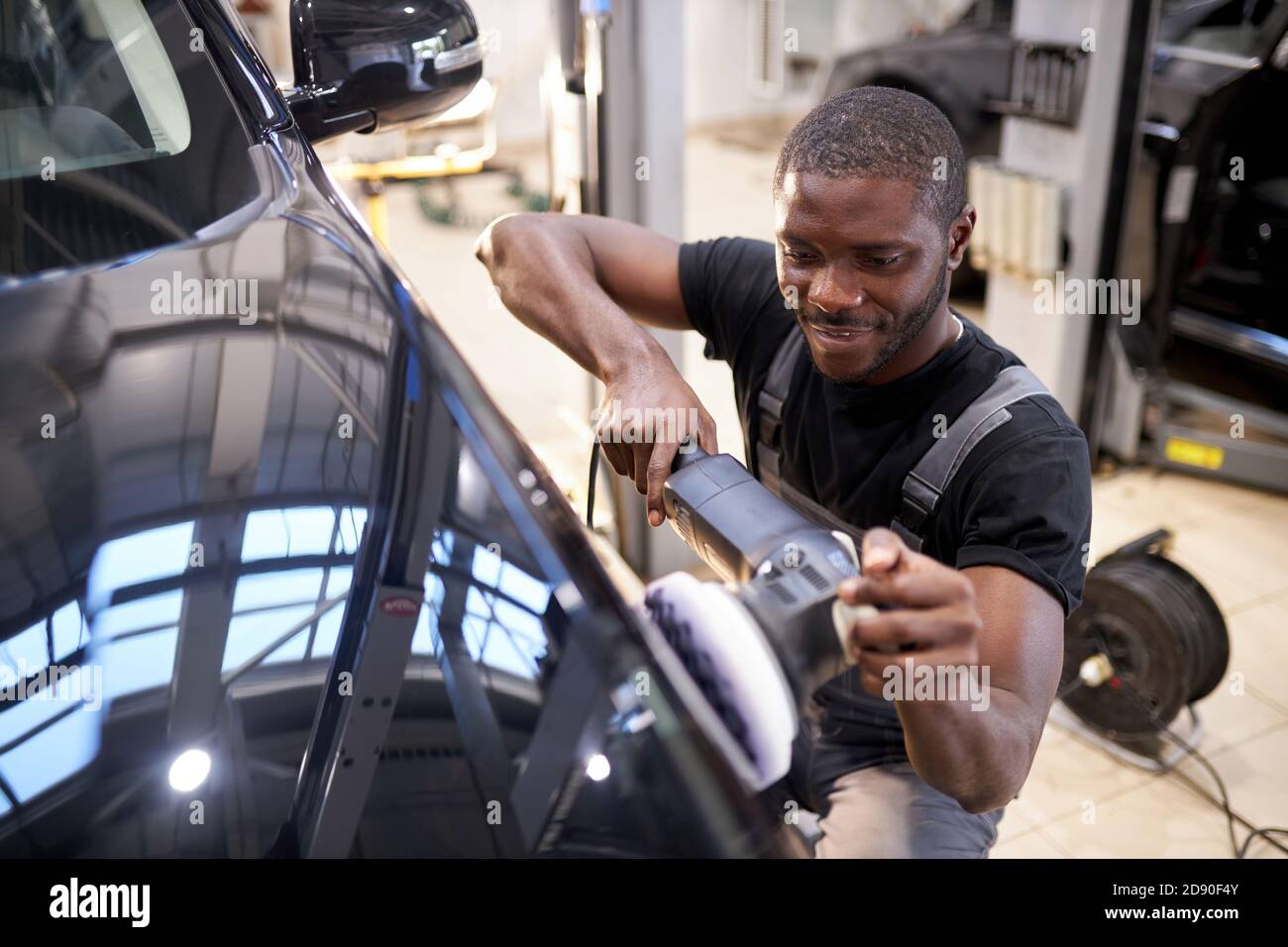automobile che descrive e lucidare il concetto. giovane lavoratore professionista africano di automobile di servizio, meccanico di automobile con lucidatrice orbitale, concetto di automobile Foto Stock