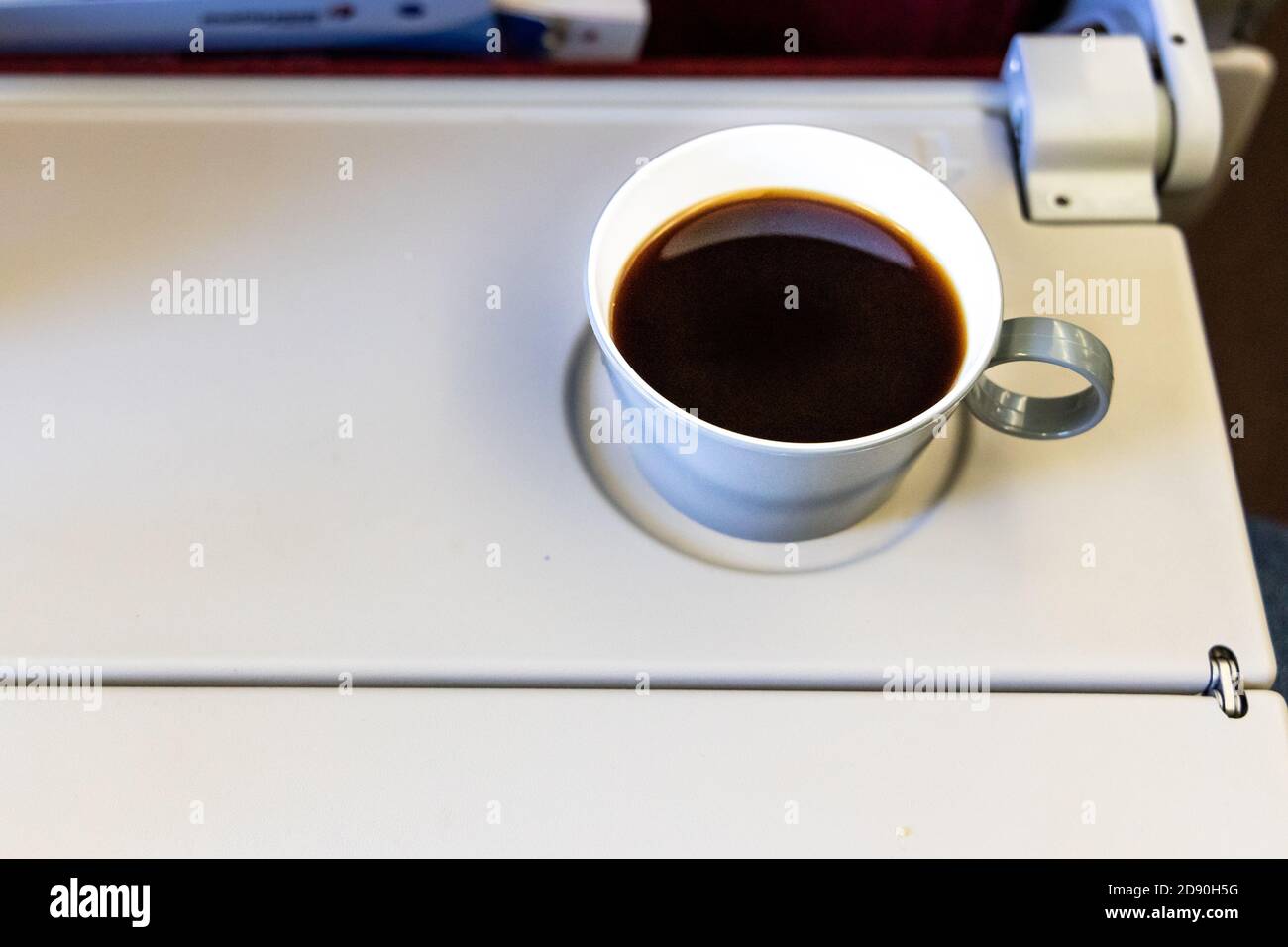 Tazza di caffè nero caldo sul tavolo in cabina aereo Foto Stock