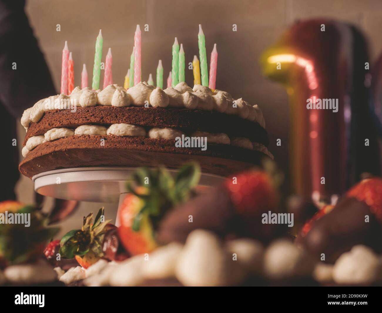 torta di compleanno con pan di spagna al cioccolato con panna e candele colorate Foto Stock