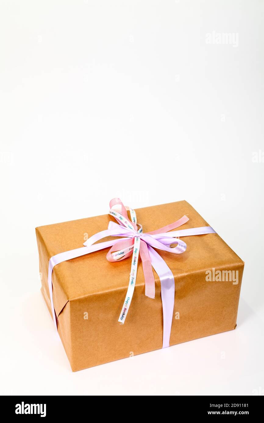 Regalo di compleanno avvolto in semplice carta marrone con nastro legato in un arco con spazio per la copia Foto Stock