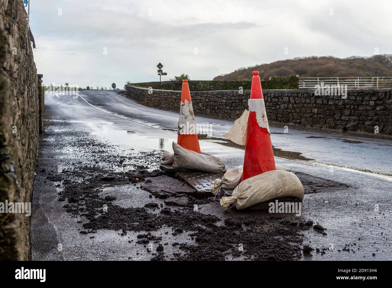 Timoleague, West Cork, Irlanda. 2 Nov 2020. La strada fuori dalla scuola nazionale di Timoleague è stata danneggiata durante la notte a causa di incessanti, forti piogge dopo un Met Eireann Warning. Il consiglio ha posto dei coni stradali per avvertire gli utenti della strada dei danni. Credit: AG News/Alamy Live News Foto Stock