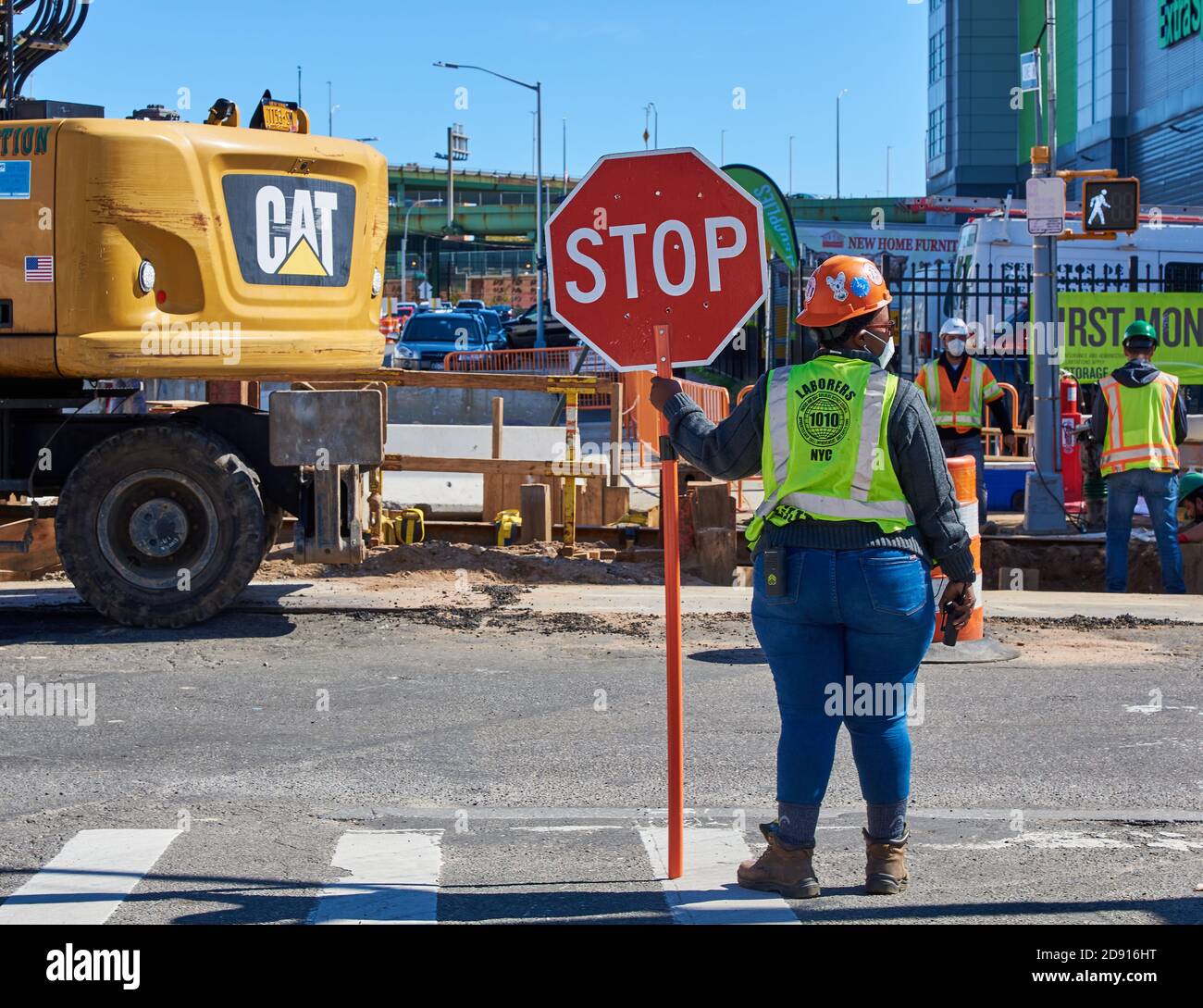 Una lavoratrice di costruzioni ha un cartello per controllare il traffico in un cantiere in Second Avenue a Sunset Park, Brooklyn Foto Stock