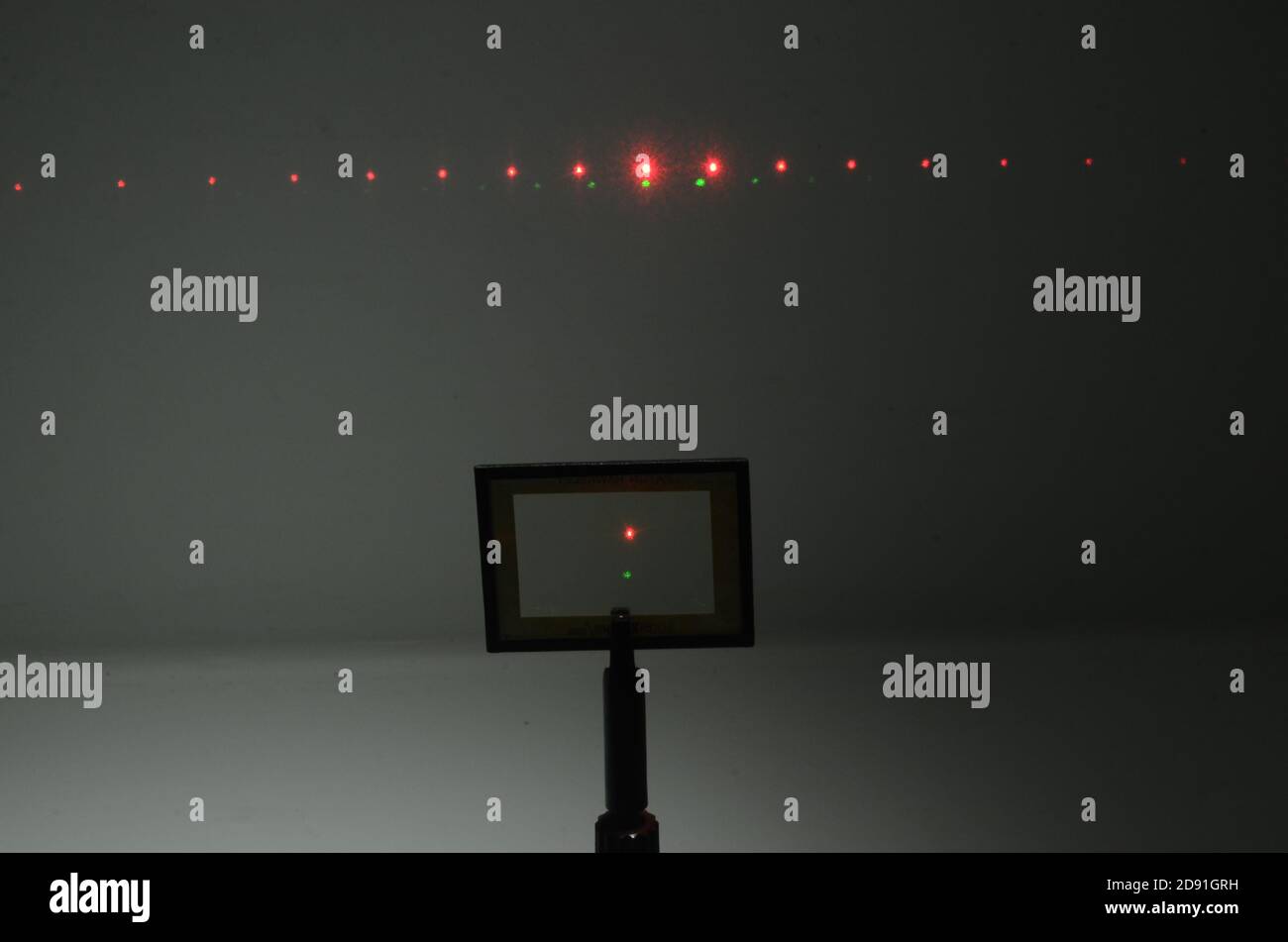 In una stanza buia, due raggi laser da una sorgente sotto la telecamera, colpiscono una griglia ottica e un modello di interferenza appears sulla parete nel backg Foto Stock