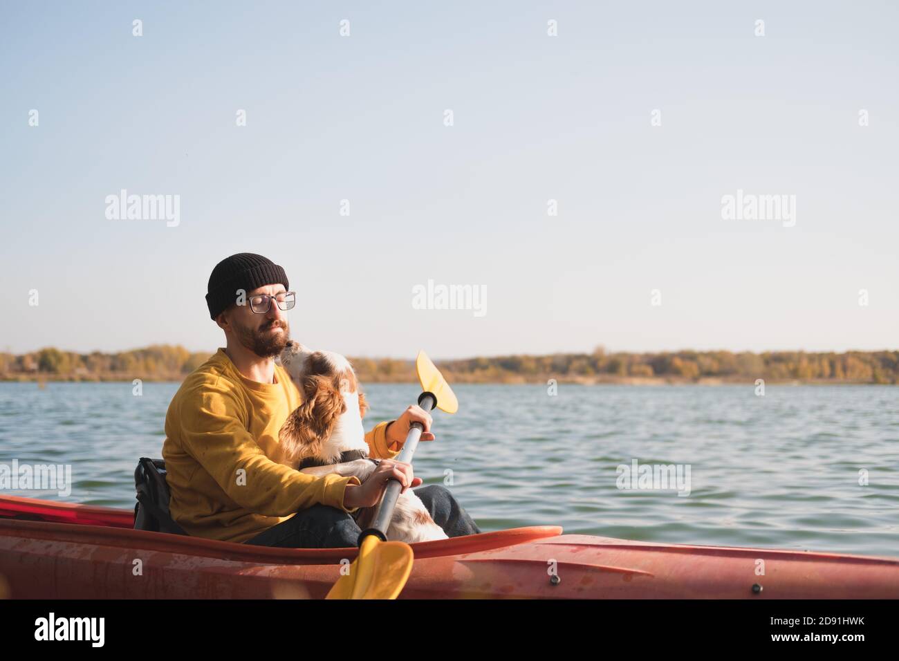 Uomo con un cane in canoa sul lago. Giovane uomo con spaniel in una barca di fila di kayak, tempo libero attivo con animali domestici, compagnia, cani d'avventura Foto Stock