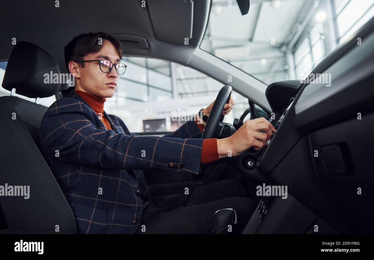 Uomo in occhiali e abiti formali seduti all'interno di moderno auto Foto Stock