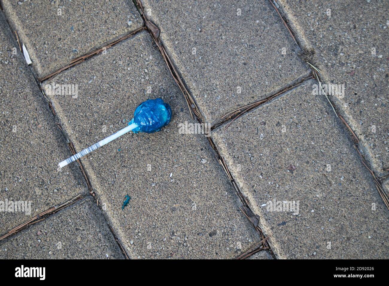 Chupa blu chups caramella sulla terra grigia di un marciapiede di strada, con spazio di copia Foto Stock