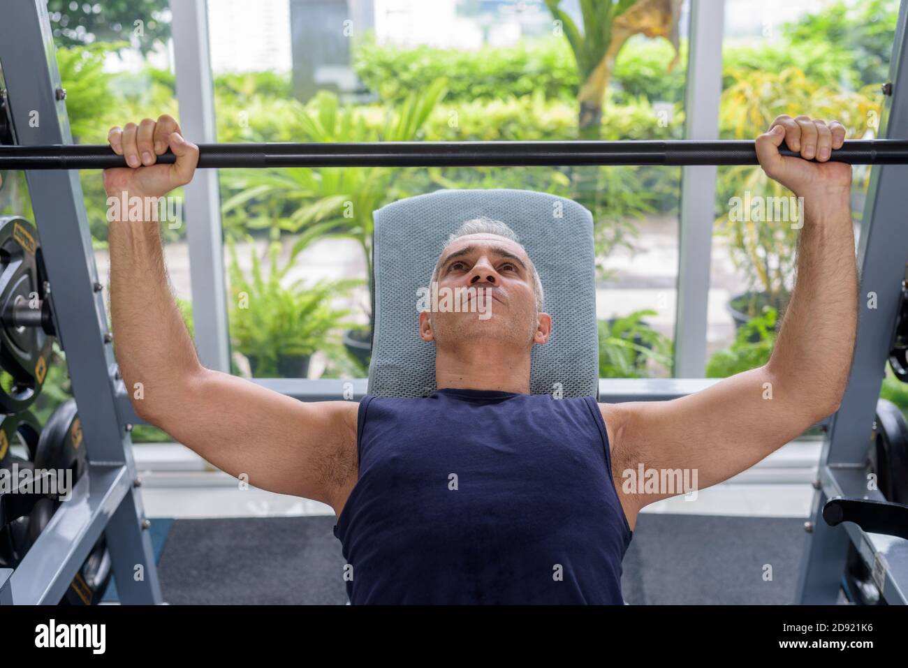 L'uomo persiano bello maturo che fa la pressa della panca alla palestra Foto Stock