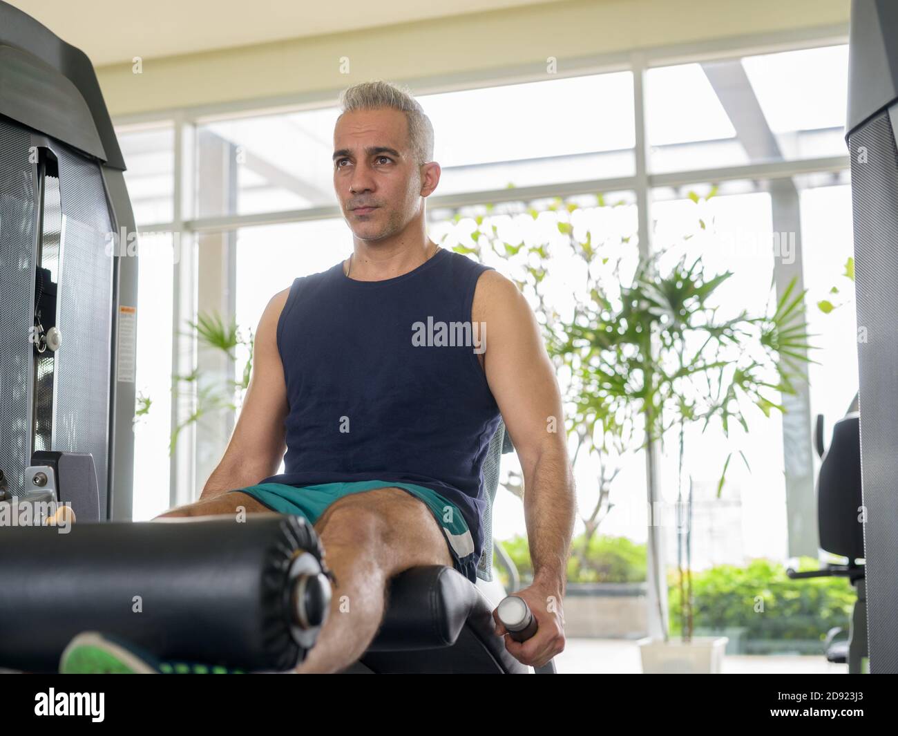 L'uomo persiano bello maturo che fa l'esercitazione di estensione della gamba al palestra Foto Stock