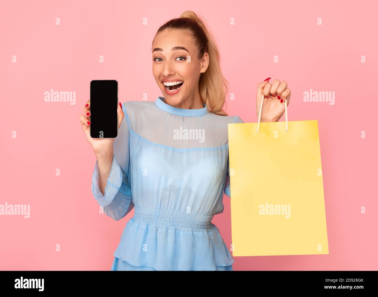 Signora eccitata che mostra schermo nero del telefono e borsa della spesa Foto Stock