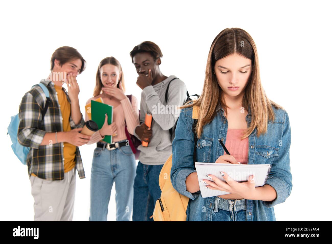 Fuoco selettivo della scrittura della ragazza sul taccuino vicino sorridente multietnico adolescenti isolati su bianco Foto Stock