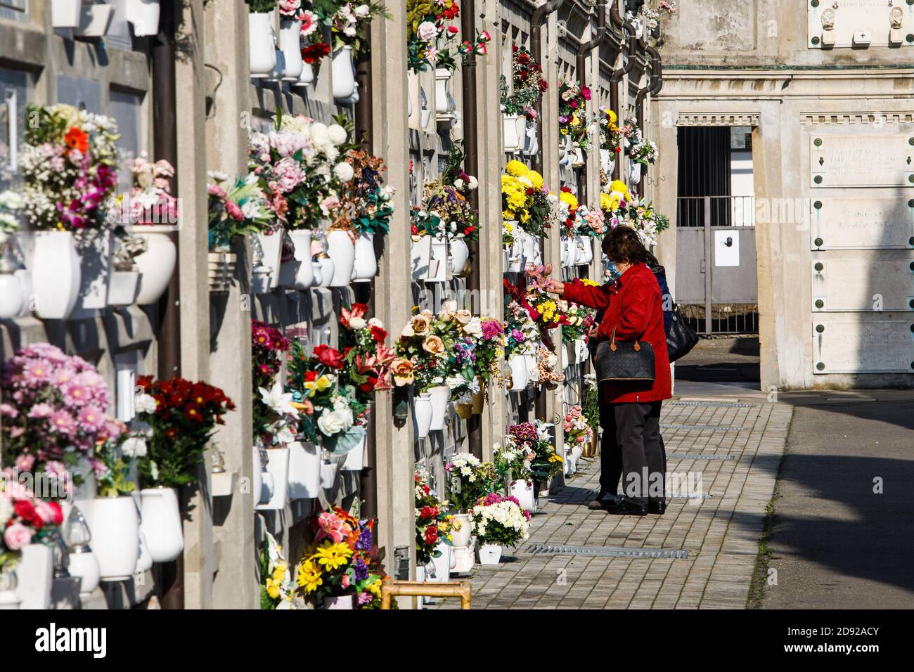 Bologna, Italia. 02 novembre 2020. Un grembo mette fiori sulla tomba della Certosa di Bologna il 2 novembre 2020 a Bologna. Molti cittadini bolognesi visitano la Certosa di Bologna (il Cimitero Monumentale della città) durante tutto il giorno dell'anima per rispettare i parenti defunti e i fiori laici, mantenere le loro tombe e candele leggere; quest'anno, tuttavia, il numero dei visitatori è significativamente ridotto a causa della pandemia covida. Credit: Massimiliano Donati/Alamy Live News Foto Stock