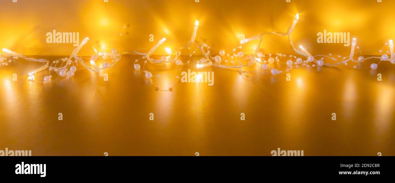 Garland di lampadine brillanti su sfondo dorato per il mockup di Natale. Luci di Natale su sfondo dorato. Umore di Natale Foto Stock