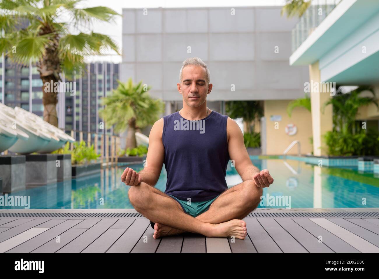 Colpo di corpo pieno di uomo persiano maturo meditando al piscina Foto Stock
